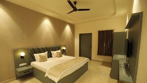 Un dormitorio moderno con cama, mesitas de noche, ventilador de techo, televisión y una puerta.