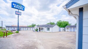 Un motel con letrero, varias unidades y zona de estacionamiento.