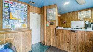 Un área de recepción con decoración de madera, un panel informativo con mapas, un cartel de HBO y un letrero de prohibido fumar.