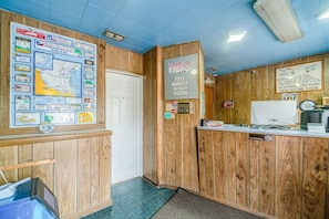 Un área de recepción con decoración de madera, un panel informativo con mapas, un cartel de HBO y un letrero de prohibido fumar.