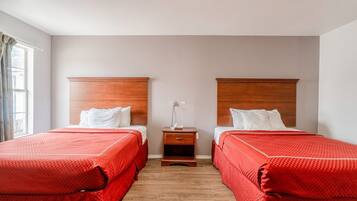 A twin room with two beds, a nightstand, and a window.