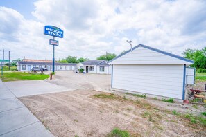 A Budget Inn motel with a parking lot, a fenced area, and a small building with a sloped roof.