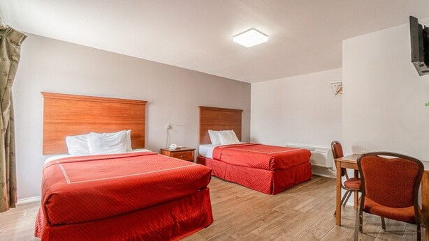 Habitación de hotel con dos camas, un escritorio y una silla.