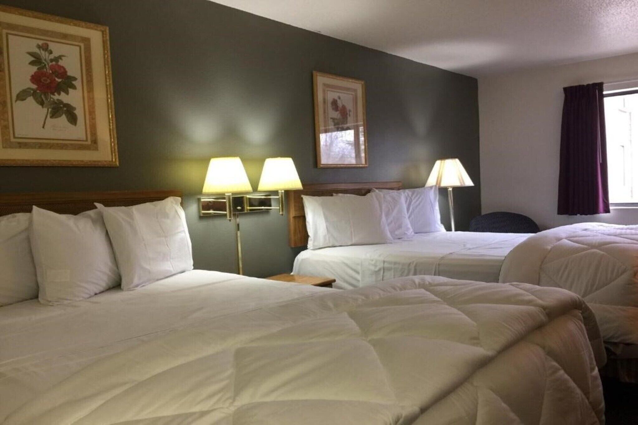 A hotel room with two beds, two bedside lamps, and framed pictures on the wall.