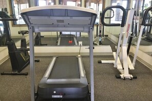 Un gimnasio con cinta de correr, elíptica y bicicleta estática.