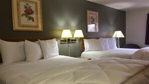 Ein Hotelzimmer mit zwei Betten, einem Kopfteil, Wandlampen und gerahmten Kunstwerken.
