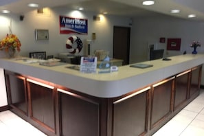 Una taquilla amb un rètol d'AmeriHost Inn & Suites, un certificat emmarcat i un ram de flors.