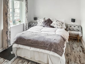 A bedroom with a bed, bedside tables, a window with curtains, and a view of the outside. - 3 bedroom accommodation in Upper Rissington (Upper Rissington)