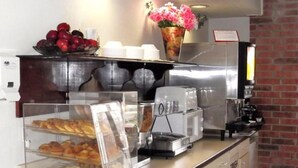 A bakery counter with pastries, a coffee machine, and a fruit bowl.
