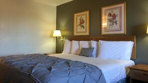 A hotel room with a bed, two wall-mounted lamps, and two framed floral pictures.