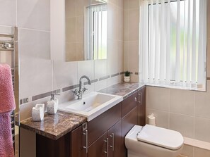 Ein Badezimmer mit Waschbecken, Spiegel, Waschtisch und Toilette.