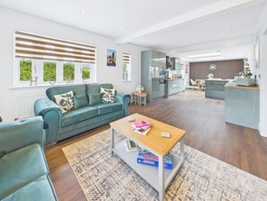 A modern living room with a sofa, coffee table, and a view of the kitchen. - 4 bedroom accommodation in Whitstable (Whitstable)