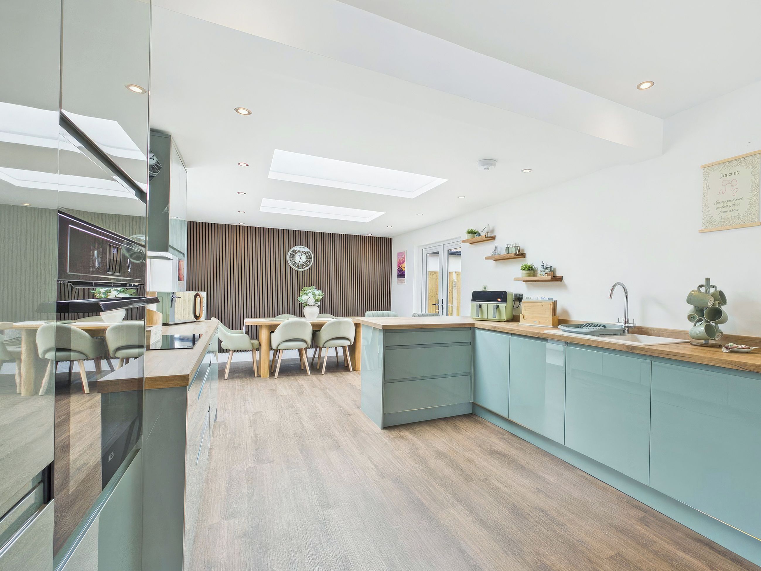 A modern kitchen with a dining area, wooden flooring, and a built-in island.