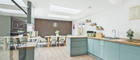 A modern kitchen with a dining area, wooden flooring, and a built-in island.