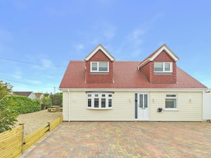 A two-story house with a red roof, beige siding, and a paved driveway. - 4 bedroom accommodation in Whitstable (Whitstable)