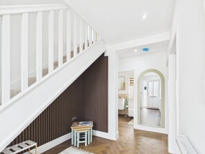 A staircase with white railings, a wooden floor, and a small table with a magazine. - 4 bedroom accommodation in Whitstable (Whitstable)