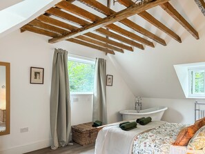 A bedroom with a sloped ceiling, a window, a built-in sink, and a bed with a floral bedspread.