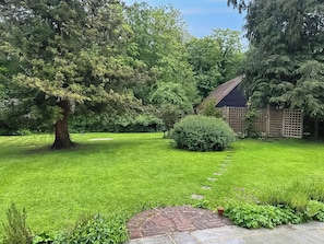 A well-maintained garden with a stone pathway leading to a wooden structure.