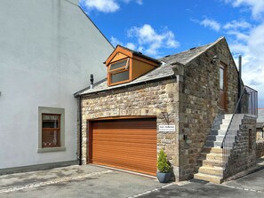 A stone building with a garage door, a small window, and a staircase leading to a second floor.