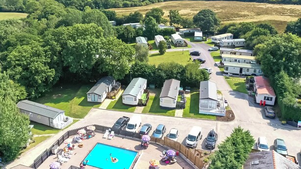 A caravan park with multiple caravans, a swimming pool, and a well-maintained lawn. - 3 steps to entrance. (Rhydlewis)