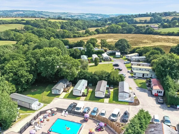 Ein Caravanpark mit mehreren Wohnwagen, einem Schwimmbad und einem gepflegten Rasen.