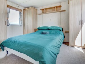 Ein Schlafzimmer mit einem Bett, einem Kleiderschrank und einem Fenster mit Vorhängen.