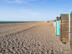 A pebble beach with wooden beach huts and a clear sky. - 2 bedroom accommodation in Hayling Island (Hayling Island)