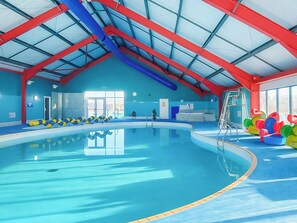 Ein Hallenbad mit hoher Decke, klaren Glaswänden und blauem Boden.