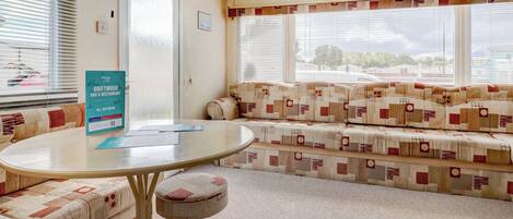Una habitación con una mesa redonda, un sofá y una ventana con persianas.