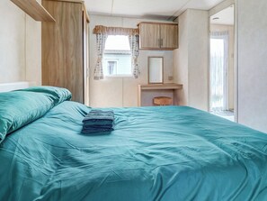 Ein Schlafzimmer mit einem Bett, einem Holzschrank, einem kleinen Tisch und einem Fenster mit Vorhängen.