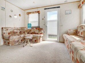 A room with a sectional sofa, a small round table, and a sliding glass door.