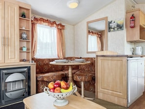 A compact kitchen with a dining area, a microwave, a small refrigerator, and a fruit bowl on the table.