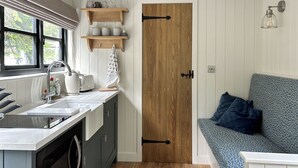 A compact kitchen with a sink, toaster, and wooden shelves. - Shepherds Hut - UK52010 (Harrogate)