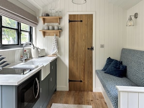A compact kitchen with a sink, toaster, and wooden shelves. - Shepherds Hut - UK52010 (Harrogate)