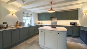 Una cocina moderna con armarios grises, una isla central e iluminación colgante.
