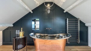 Un baño moderno con una bañera independiente, un tocador con espejo y una ventana con luz natural.