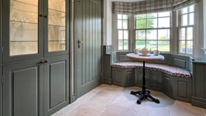 Una habitación de esquina con ventanal saliente, una mesa con una silla y un mueble con puertas de cristal.