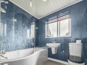 Ein Badezimmer mit freistehender Badewanne, einem wandmontierten Waschbecken und einer Toilette.