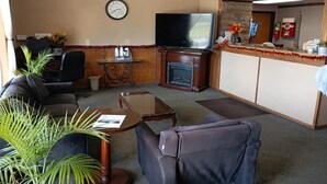 Un salon comprenant un canapé, un fauteuil, une table basse, une cheminée, un téléviseur et un comptoir d’accueil.