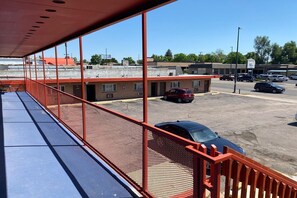 Um estacionamento com um edifício ao fundo, uma área coberta azul com grades e vários carros estacionados.