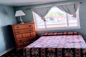 Ein Schlafzimmer mit einem Bett, einem Schminktisch und einem Fenster mit Vorhängen.