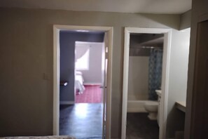 A hallway leading to a bathroom with a toilet and shower. - 2 Queen Beds Suite with Kitchenette (Englewood CO)