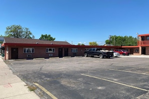 A motel with a red exterior, a parking lot, and a black pickup truck parked in the lot. - 2 Queen Beds Suite with Kitchenette (Englewood CO)