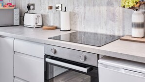 Uma cozinha com forno embutido, torradeira, garrafa de vidro e um vaso com flores.