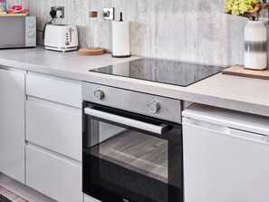 Eine Küche mit Backofen, Toaster, einer Glasflasche und einer Blumenvase.