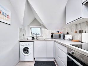 Eine moderne Küche mit Einbauwaschmaschine, Mikrowelle und Toaster.