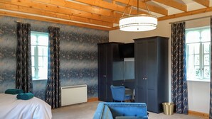 Ein Schlafzimmer mit einem Bett, einem blauen Sofa, einem Kleiderschrank und einem Schreibtisch.