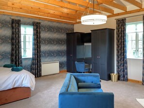 Ein Schlafzimmer mit einem Bett, einem blauen Sofa, einem Kleiderschrank und einem Schreibtisch.