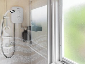 Una ducha con cabezal de ducha de mano y panel de control en la pared.