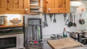 Keittiössä on puukuvioiset kaapit, mikroaaltouuni, leivänpaahdin ja erilaisia keittiövälineitä, jotka on ripustettu seinälle.